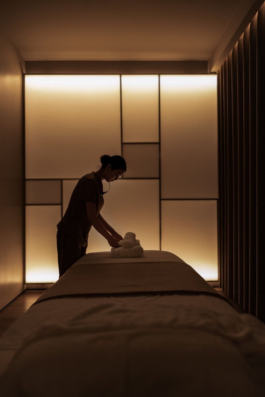 A therapist preparing a treatment table in a softly lit room